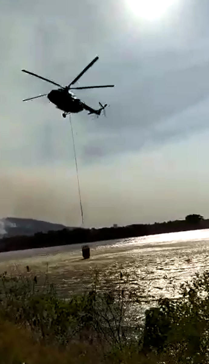 A video grab of a chopper lifting water from Berambadi lake near Bandipur forest area to douse the fire in the forest on Monday.