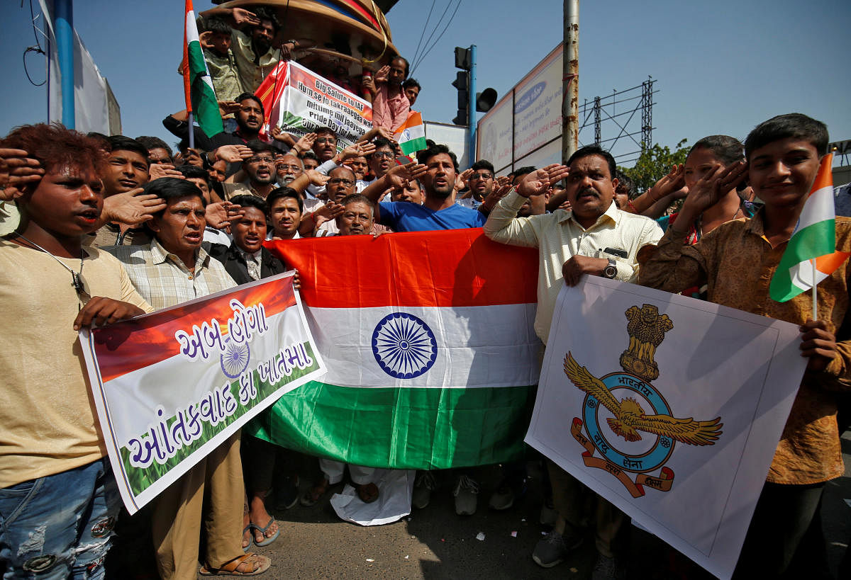 People hold national flags and an Indian Air Force flag as they salute to celebrate after Indian authorities said their jets conducted airstrikes on militant camps in Pakistani territory, in Ahmedabad, India, February 26, 2019. REUTERS