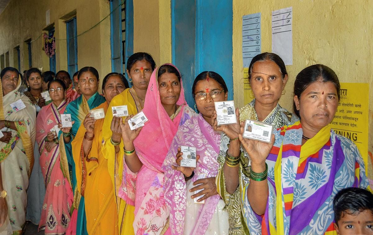 Voters show their identity cards as they stand in a queue at a polling station to cast their vote for the Gram Panchayat elections at Masur village, in Karad. PTI/FILE