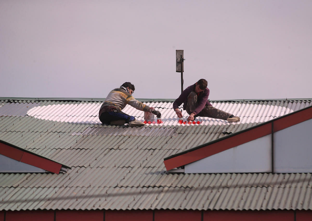 Workers paint a Red Cross sign on the rooftop of a hospital in Srinagar. (Reuters Photo)