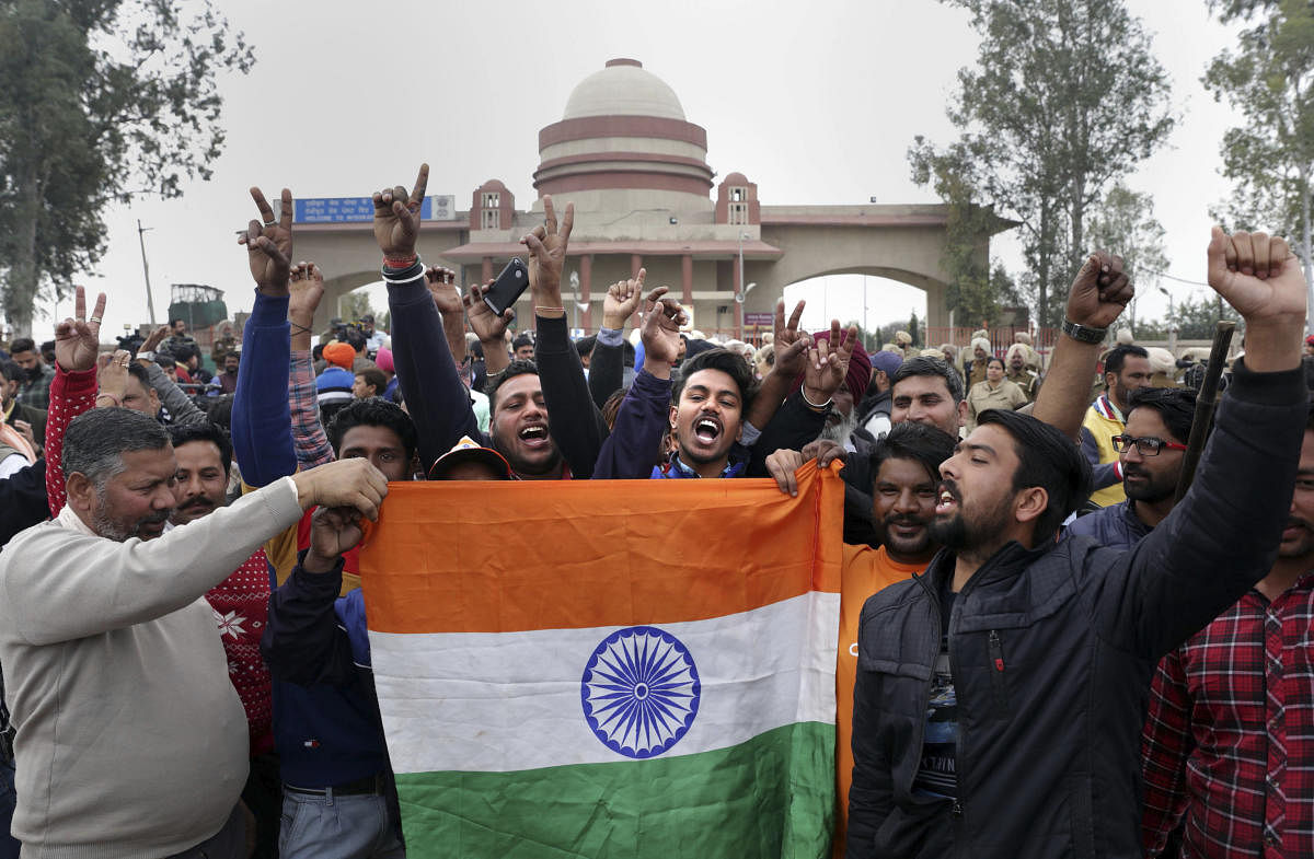 Attari: People jubilate with a Tricolour as they wait for the arrival of IAF pilot Wing Commander Abhinandan Varthaman at Attari-Wagha border near Amritsar, Friday, March 1, 2019. Varthaman, who was captured by Pakistan after his jet went down following a strike by an enemy missile, is expected to be released today. (PTI Photo)
