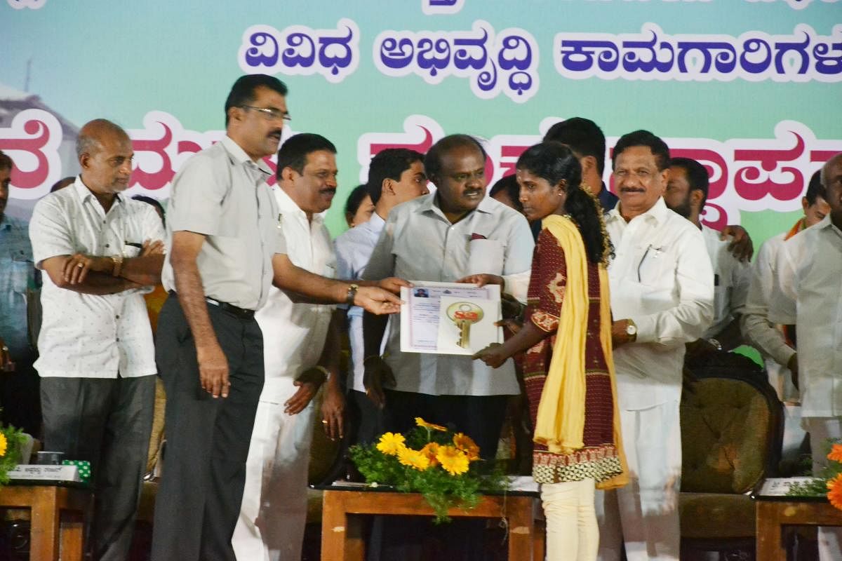 Chief Minister H D Kumaraswamy hands over the title deed of a house to one of the Diddalli evacuees at a programme in Kushalnagar on Thursday.