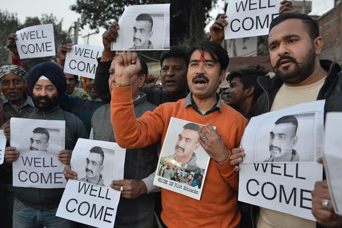 Indian people hold placards and photographs of Indian Air Force pilot Abhinandan Varthaman, as they celebrate the announcement of his soon release, in Amritsar on February 28, 2019. - Pakistan said on February 28 it will release a captured Indian pilot in