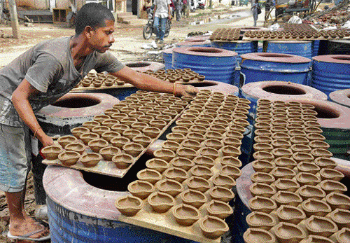 A man arranges diyas for drying. A potter gives final shape to a pot.