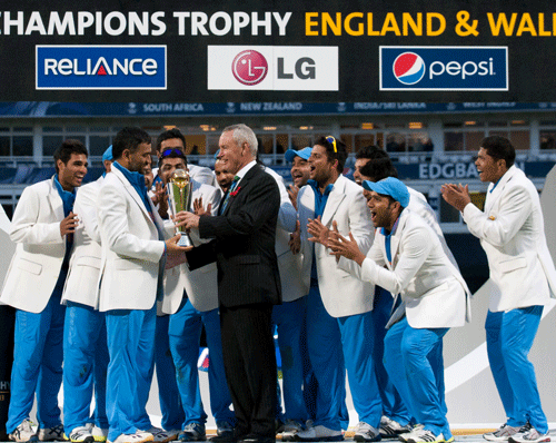 Mahendra Singh Dohni, second left, receives the trophy from ICC President Alan Isaac after India won the ICC Champions Trophy Final cricket match by beating England at Edgbaston cricket ground, Birmingham, England, Sunday June 23, 2013. (AP Photo/