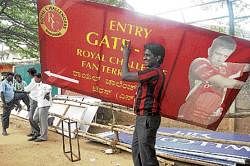 A worker carrying away flexes outside Chinnaswamy stadium in Bangalore on  Sunday. DH photo