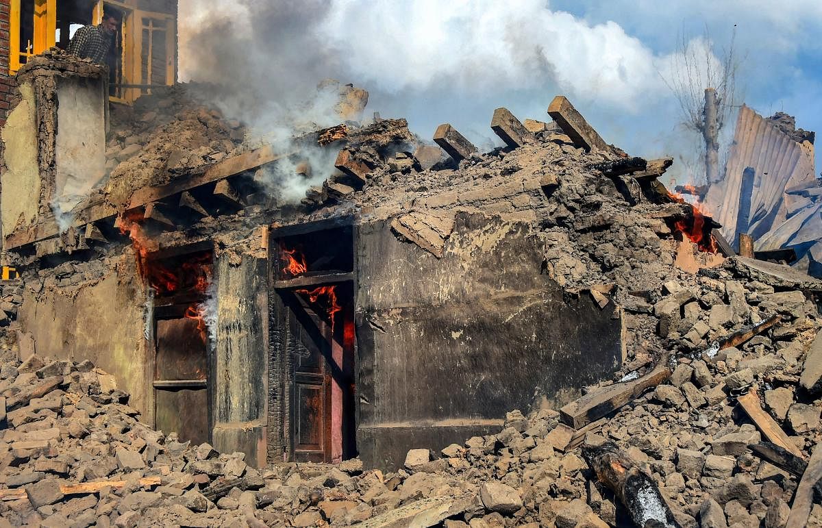 Smoke rises from a house destroyed during a gunbattle between security forces and militants at Reshi Mohlala area of Tral in Pulwama district of South Kashmir, Tuesday, March 5, 2019. Two local militants of the Hizbul Mujahideen have been killed in an ove