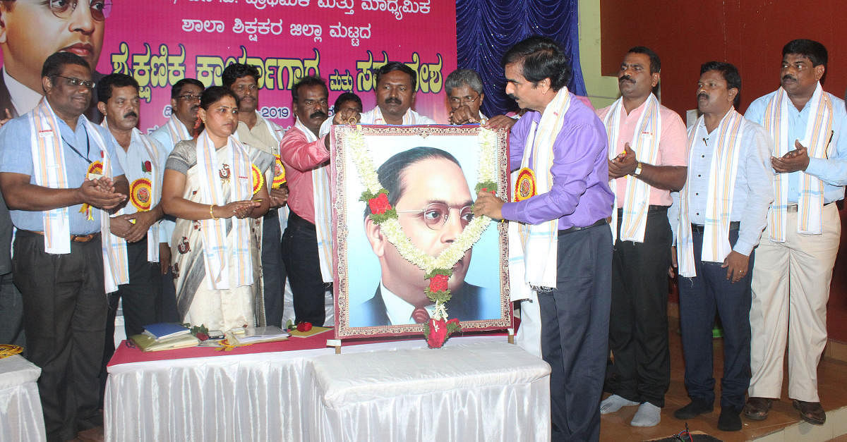 DDPI Sheshashayana Karinja inaugurates the district-level education convention in Udupi by garlanding the portrait of Ambedkar.