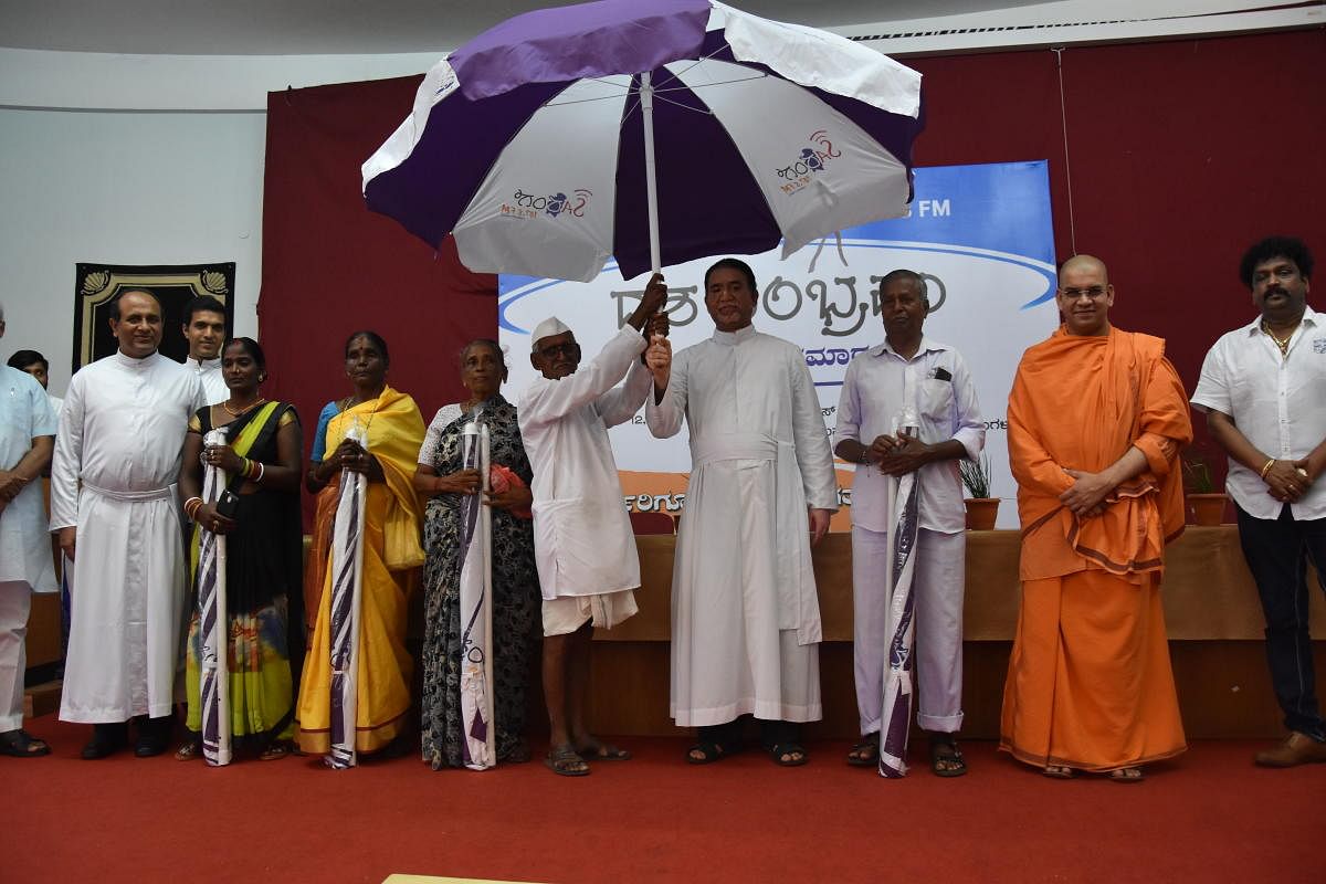 St Aloysius College Principal Dr Praveen Martis presents an umbrella to M M Bilagi, popularly called ‘Samosajja’, at the decennial celebrations of Radio Sarang.