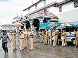 Taking no chances: Police personnel stand in front of Dharmasthala before the arrival of Chief Minister B S Yeddyurappa in Mangalore on Sunday. Dharmadhikari Veerendra Heggade (inset) says separate arrangements have been made for the chief minister and JD(S) leader H D&#8200;Kumaraswamy who will offer prayers at the temple on Monday. DH Photo