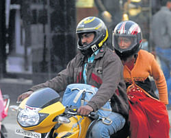 Bike riders covered in sweaters, helmets to keep away the chill in Mysore on Friday. DH photo