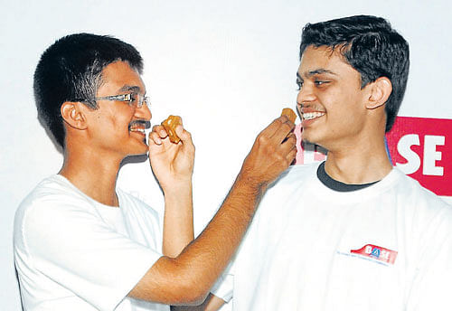 Prajwal K A, 1st rank holder in engineering, and Hemanth Amardeep Santhoor, who got 1st rank in medical, share sweets in Bangalore on Tuesday. DHPhoto/B K Janardhan