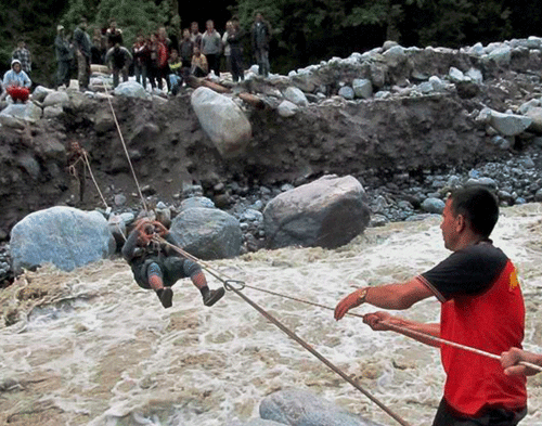 Army personnel rescuing pilgrims with the help of a rope bridge at Lambagar in flood ravaged Uttarakhand. PTI Photo