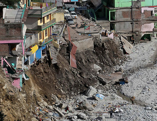 In this June 22, 2013 file photo, vehicles are parked near the buildings damaged by floods and landslides in Govindghat in the northern India state of Uttarakhand, India. A top Indian official said more than 5,700 people were missing since last month's devastating floods that ravaged northern India are now presumed dead. (AP Photo/Rafiq Maqbool, File)