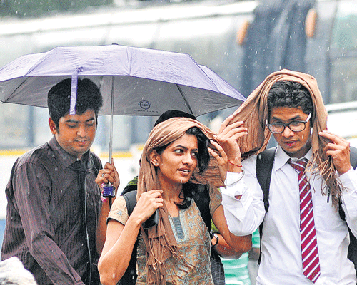 FRIENDS IN NEED: Students cover themselves as sudden rain lashed the City on Friday. DH PHOTO