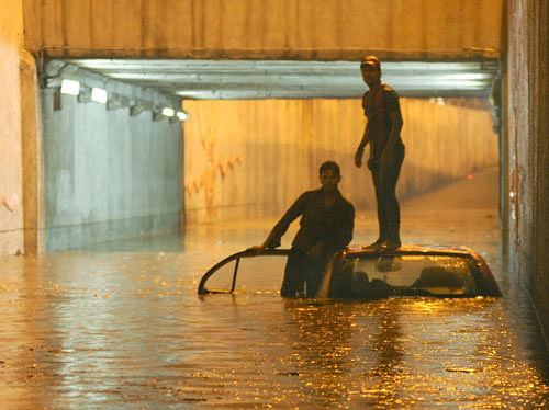 Occupants of a submerged car stranded at the waterlogged K&#8200;R Circle underpass in Bangalore on Saturday. DH Photo/ Kishor Kumar Bolar