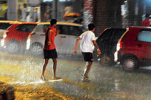 soothing showers:  Two men run for cover following rain on Brigade Road on Tuesday night. DH PHOTO