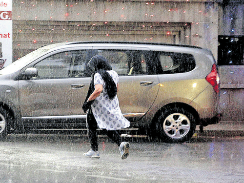 A girl rushes for cover on Kumara Krupa Road as showers lashed the City on Friday. dh Photo