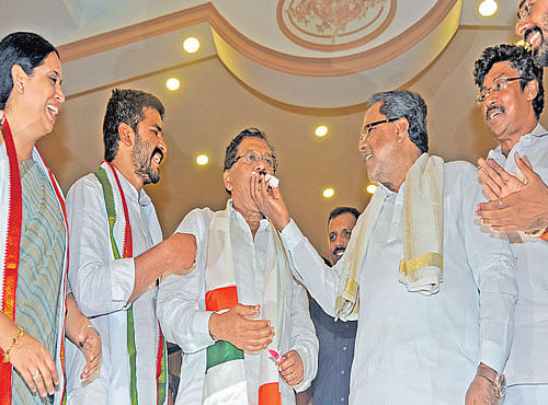 Chief Minister Siddaramaiah offers cake to KPCC President G Parameshwara at a function organised to mark latter's completion of five years as president of the State Congress unit, in Bengaluru on Friday. KPCCwomen's wing President Lakshmi Hebbalkar, AICC Secretary Selvakumar (extreme right) and others are seen. DH PHOTO