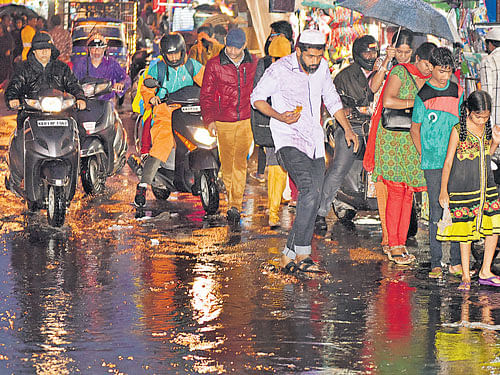 Shoppers struggle to walk on the waterlogged Meenakshi Koil Street in Shivajinagar on Wednesday.