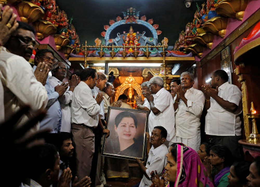 Well wishers of Tamil Nadu Chief Minister Jayalalithaa Jayaraman hold her portrait as they pray at a temple in Mumbai. PTI