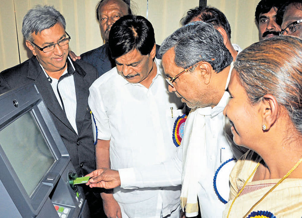 Chief Minister Siddaramaiah withdraws cash from an ATM, said to be his first experience, after inaugurating the branch of The Mysuru Merchants Cooperative Bank in Mysuru  on Sunday. Dh photo