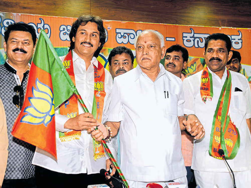 BJP state president B S Yeddyurappa welcomes former minister Kumara Bangarappa and former legislator J D Nayak to the party by handing over the party flag, in Bengaluru on Thursday. Party leaders Beluru Gopalakrishna, Renukacharya and others are seen. DH Photo