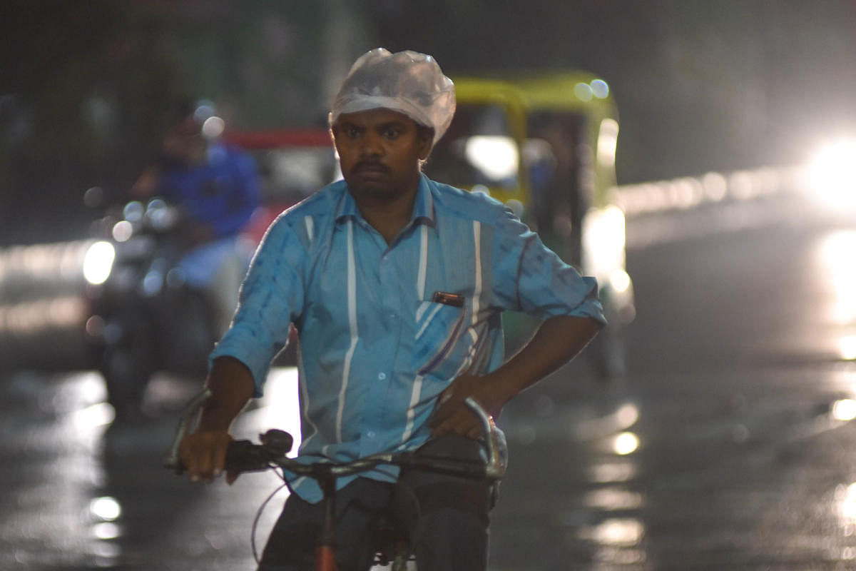 A man wearing plastic cover to protect from rain at Brigade road in Bengaluru on Friday. Photo by S K Dinesh