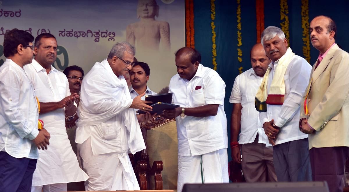 Dharmasthala Dharmadhikari D Veerendra Heggade and Chief Minister H D Kumaraswamy exchange the Memorandum of Understanding towards the rejuvenation of lakes under Kere Sanjeevini programme of the state government. District in-charge minister U T Khader an
