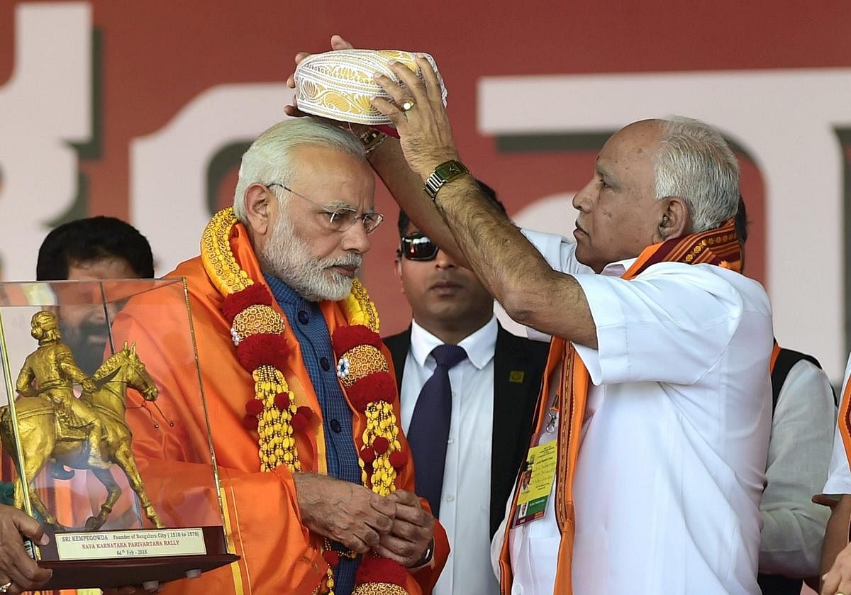 BS Yeddyurappa presents a headgear to Narendra Modi. PTI file photo