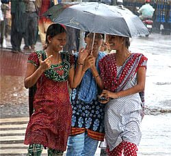 Girls share an umbrella as they walk in a drizzle in Mangalore on Wednesday. PTI Photo