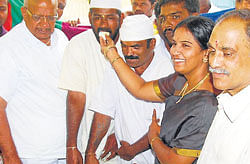 Mysore taluk panchayat former president Manjula Manjunath offers sweets to an inmate, who was released from&#8200;Central Prisons Mysore on Sunday. MLA&#8200;M&#8200;Satyanarayana and chief superintendent of prisons P&#8200;N&#8200;Jayasimha are seen.  dh photo