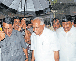 Former chief minister Yeddyurappa leaves protest venue as heavy rain lashed Bangalore on Saturday. DH Photo