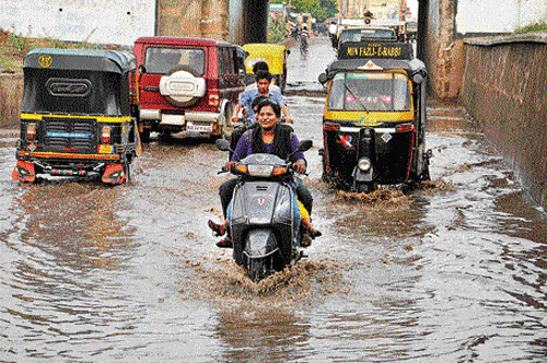 Commuters ride through a flooded road in Bellary on Tuesday. DH PHOTO