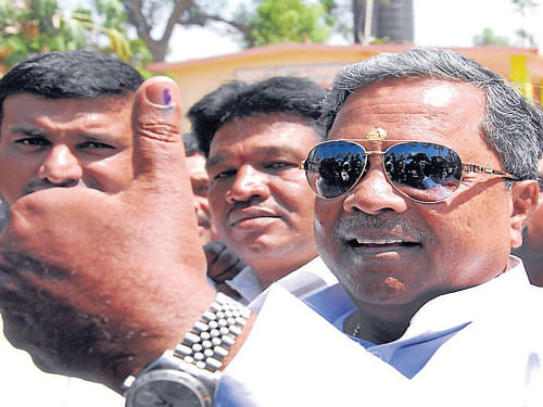 Siddaramaiah shows thumbs up after voting at Siddaramanahundi in Mysore district. DH Photo
