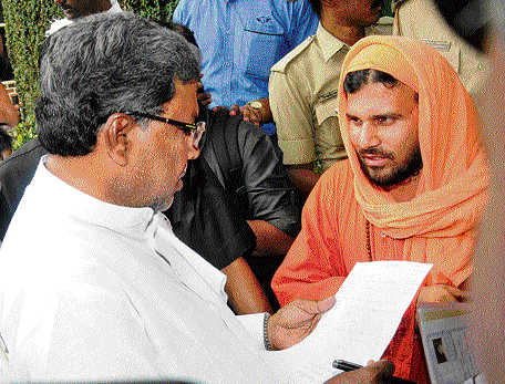 Selfy-styled 'swami' Ramamurthy submits a letter to Chief Minister Siddaramaiah in Bangalore on Monday. DH photo