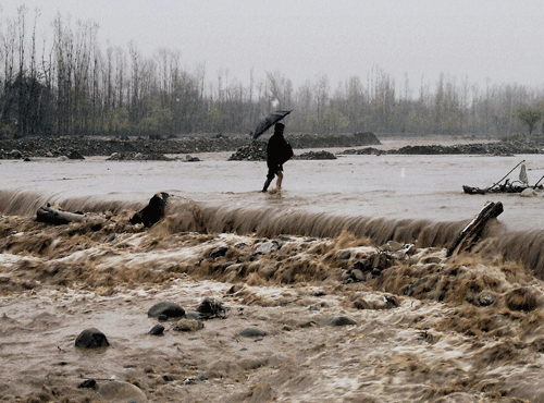 A man passes through a submerged bridge in a flooded Larkipora area in Anantnag, south Kashmir on Sunday. PTI Photo