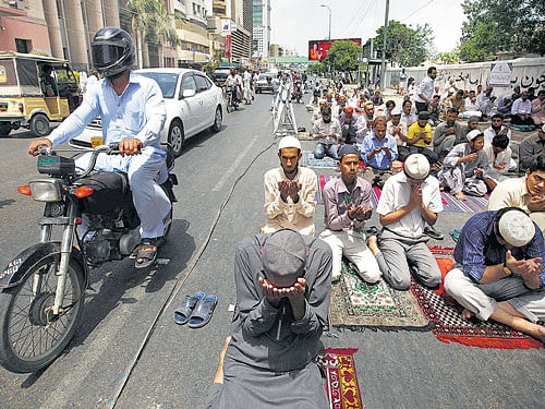 sense and sensibility: Vehicles move past men offering their Friday prayers near a mosque during the holy month of Ramzan in Karachi, Pakistan. The forced piety enshrined in Pakistan's law and Karachi's contempt for the working poor has killed thousands this June. REUTERS