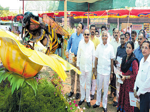 Minister for Higher Education T B Jayachandra takes a look at the model of a bee sitting on a flower after inaugurating the two-day 'Jenina Jhenkara Mattu Savayava Mela,' an exhibition on honey and organic products, at Kadri Park in Mangaluru on Saturday. MLA&#8200;J&#8200;R&#8200;Lobo, Deputy Commissioner&#8200;A&#8200;B&#8200;Ibrahim and ZP&#8200;CEO&#8200;P&#8200;I&#8200;Sreevidya look on. DH&#8200;photo