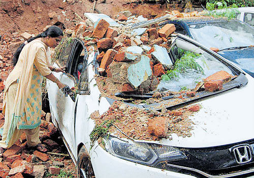Nature's fury: A woman checks her car which was damaged in a wall collapse during a storm in Hyderabad on Friday.