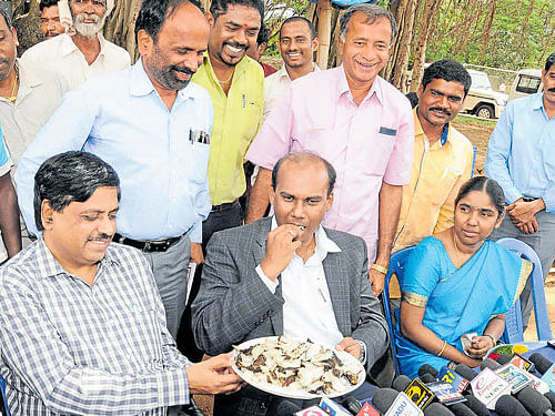 Tribal treat Deputy Commissioner D&#8200;Randeep and Zilla Panchayat&#8200;CEO&#8200;P&#8200;Shivashankar taste 'Noregenasu', a food item prepared by the tribals, at the Scouts and Guides Grounds in Mysuru on Tuesday. DH PHOTO