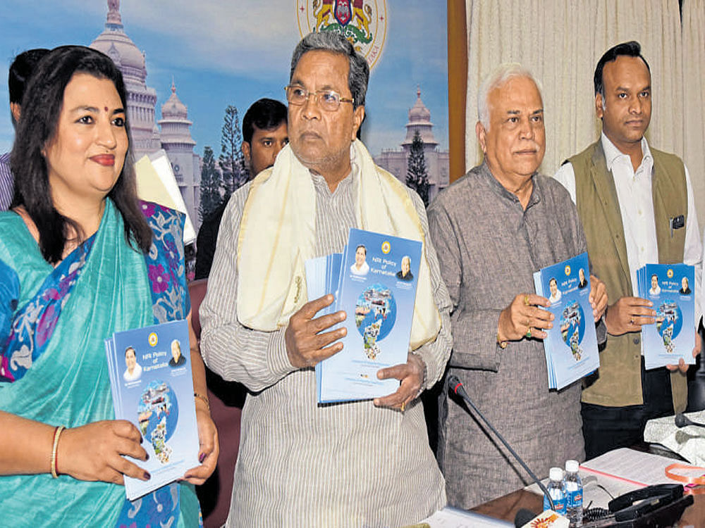 Chief Minister Siddaramaiah releases the NRI Policy of  Karnataka in Bengaluru on Friday. (From left) NRI Forum Deputy Chairperson Arathi Krishna, Large and Medium Scale Industries Minister R V Deshpande and Tourism Minister Priyank Kharge are seen. DH Photo