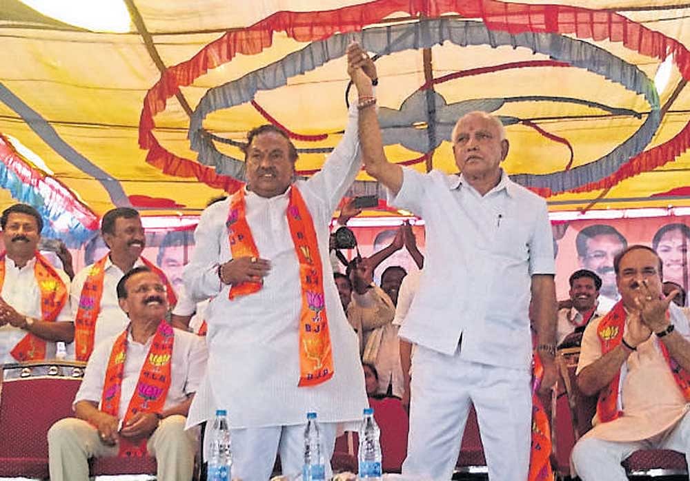 BJP leaders K&#8200;S&#8200;Eshwarappa and B&#8200;S&#8200;Yeddyurappa hold hands to signal that all's well, at a party rally at Gubbi in Tumakuru district. DH photo