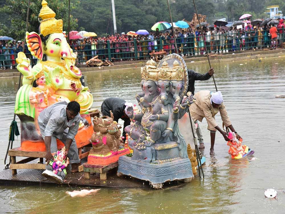 People brave rain during the immersion of Ganesha idols in Halasuru lake. DH Photo