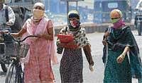 MASKED AGAINST SUN: Girls with their heads and faces  covered with veils walk past braving the heat in Gulbarga on Monday. DH Photo
