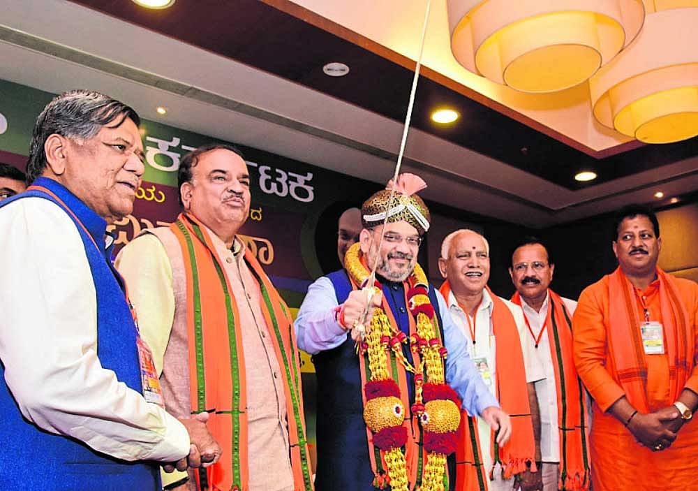 BJP national president Amith Shah holds a sword presented to him at a meeting of the party MPs and legislators in a hotel in Bengaluru on Sunday. BJP leaders Jagadish Shettar, Ananthkumar, B S Yeddyurappa, D V Sadananda Gowda and Vishwanth are seen. DH Photo