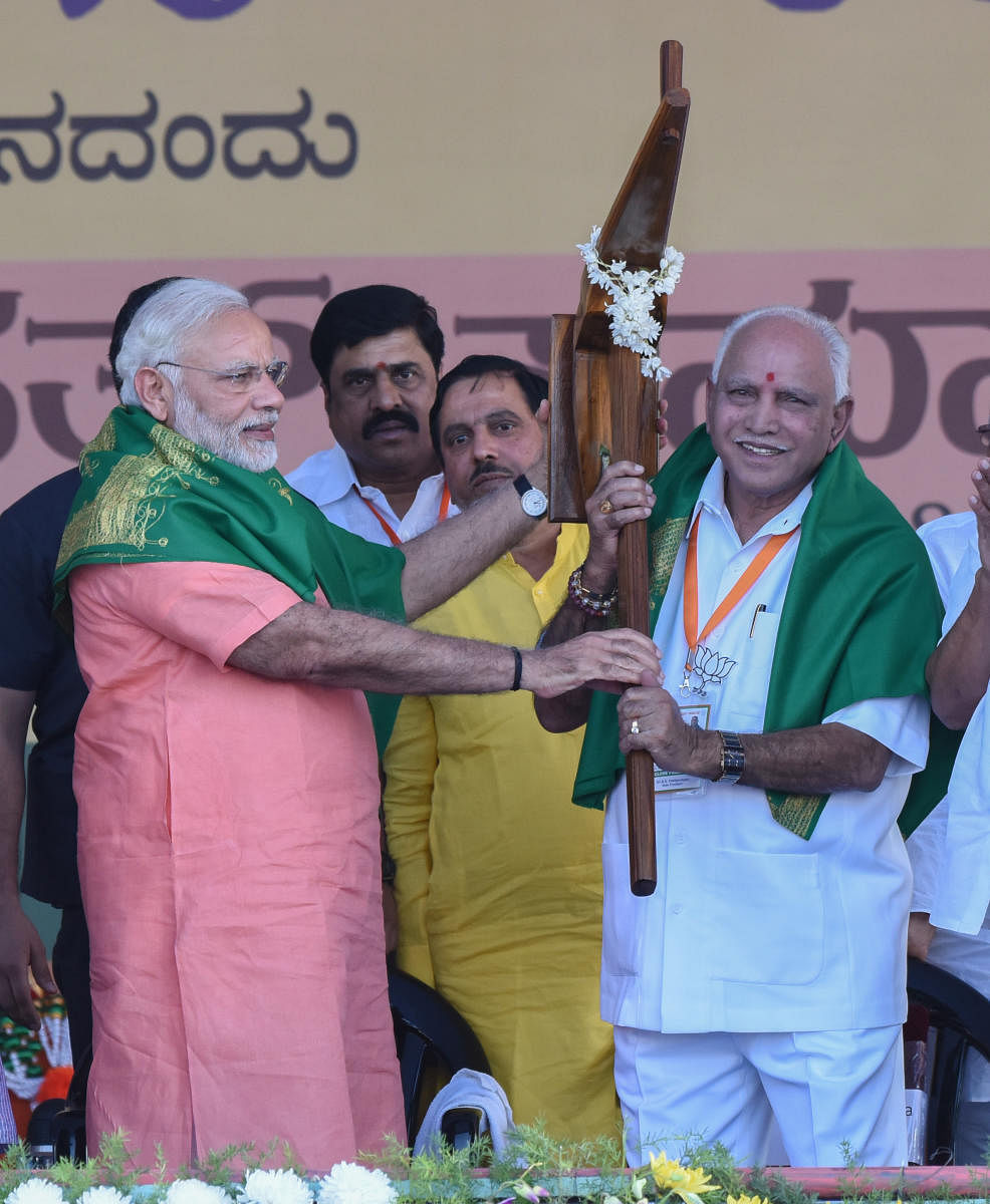 Prime Minister Narendra Modi presents a plough to BJP state president B S Yeddyurappa at the farmers' rally organised by the party in Davangere on Tuesday. MP G M Siddeshwara, Union Minister Ananth Kumar, MP Sriramalu and others were present. dh photo