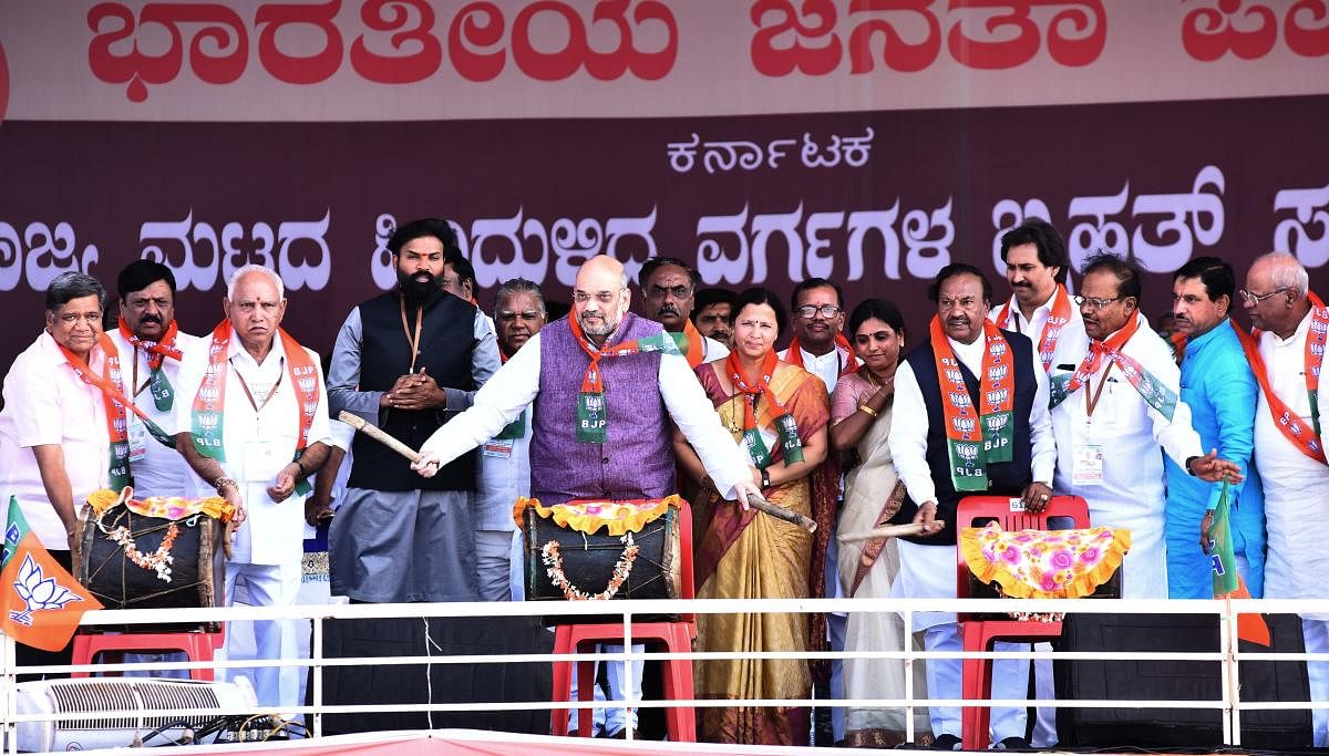 BJP National President Amit Shah beats drum to mark the inauguration of the BJP's State-level backward classes convention at Kaginele in Haveri district on Tuesday. B S Yeddyurappa, B Sriramulu, K S Eshwarappa and others are present.