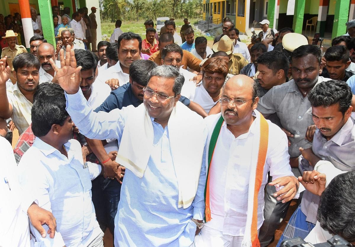 Karnataka Chief Minister Siddaramaiah waves at his supporters after voting in the Karnataka Assembly elections 2018, at Hundi village in Mysore on Saturday. (PTI Photo)