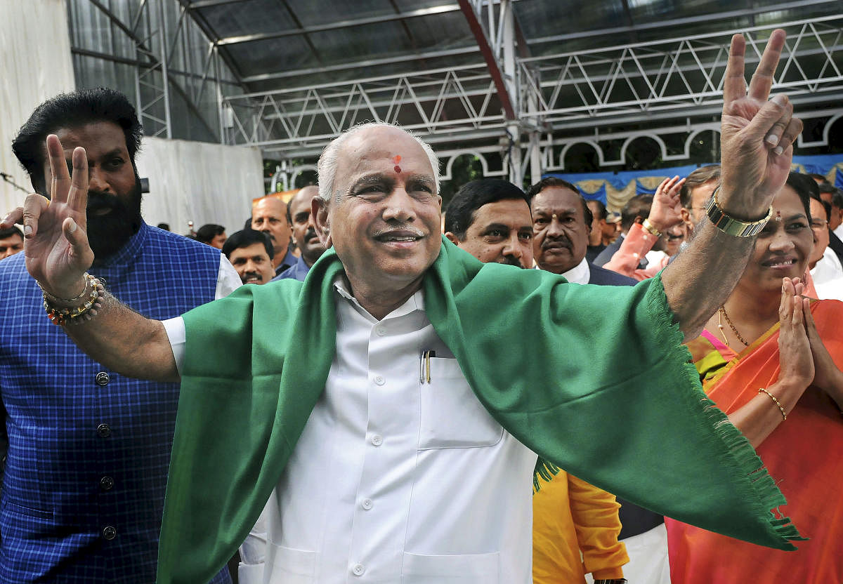 Bharatiya Janata Party (BJP) leader B. S. Yeddyurappa flashes the victory sign as he arrives at Governor's House to take oath as Chief Minister of Karnataka state, in Bengaluru. PTI Photo
